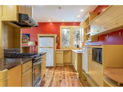The kitchen has a gas stove, a large double sink, and ample storage in custom height cabinetry