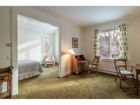 Separated from the first floor living spaces by a private office or sitting room, the first floor primary suite includes walk-in closet, a full bath with jacuzzi tub, and a comfortable bedroom with high ceilings and broad windows overlooking the landscape.