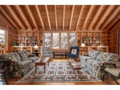 Spacious living room with a cathedral ceiling, built-in bookcases and cabinetry, and a wood stove. With wide-board pine floors throughout, and a second-floor book loft that doubles as an office area, this room offers endless opportunities. French doors provide access to a brick terrace facing the woods and a lovely English rock garden